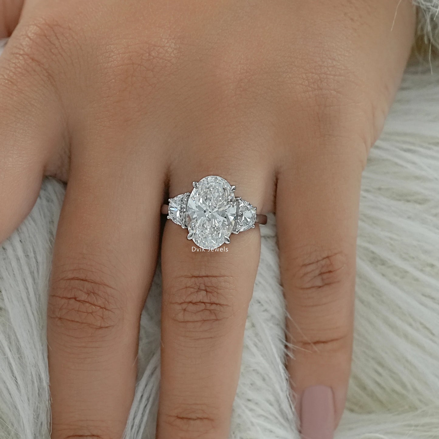 Oval diamond ring with half moon side stones worn on a finger for bridal look