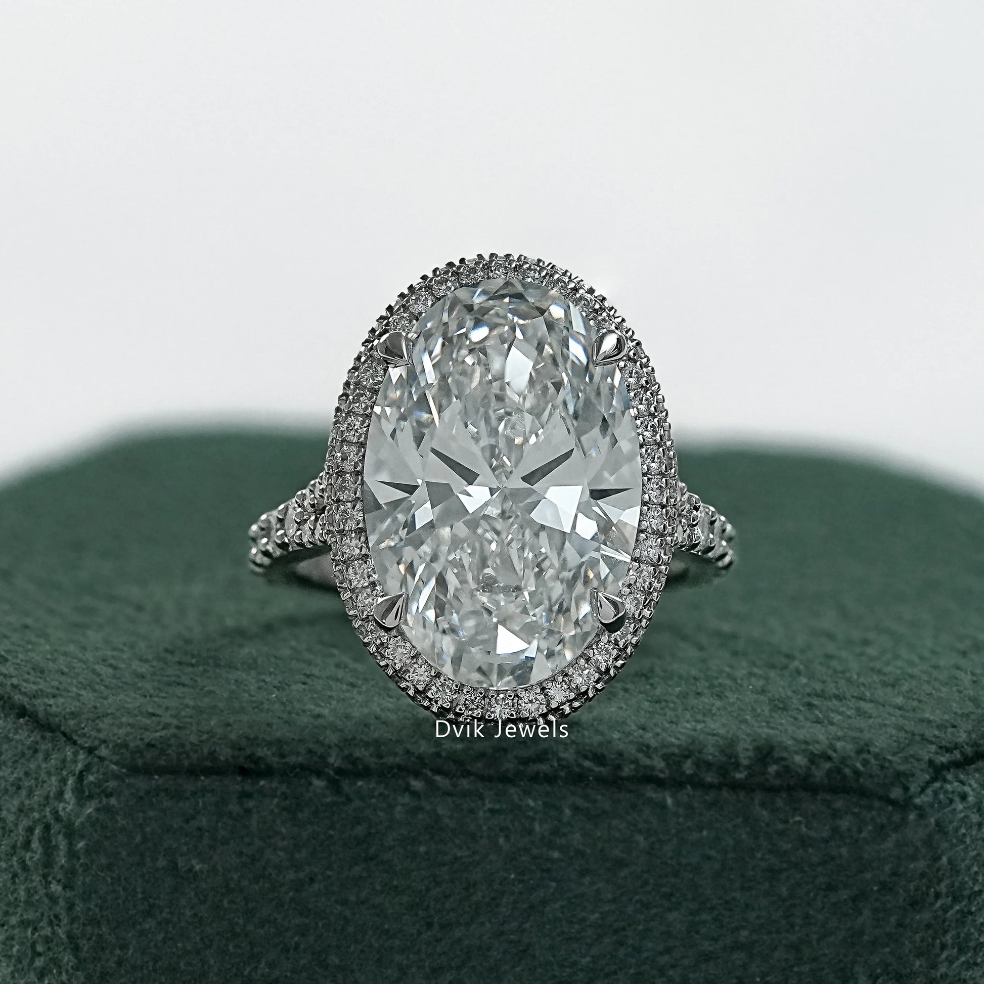 Oval halo pave engagement ring held to show the shimmering diamond border