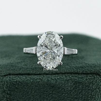 Dvik Jewels Oval Engagement Rings with Side Stones front view placed on dark green velvet.