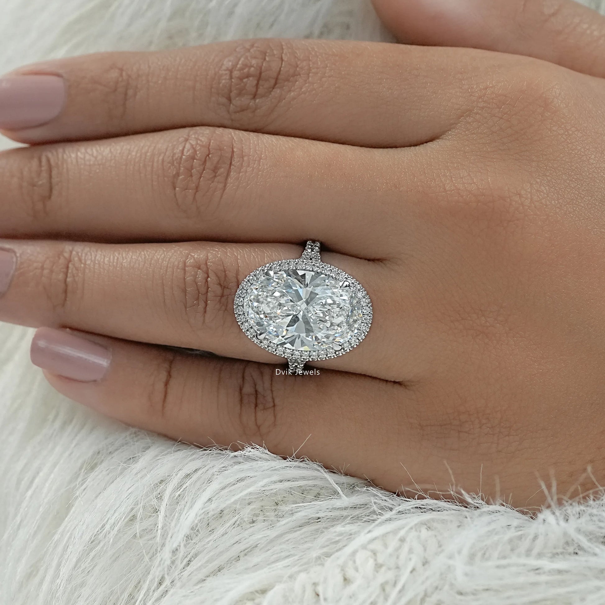 Lab diamond oval engagement ring held to showcase the delicate pave band.