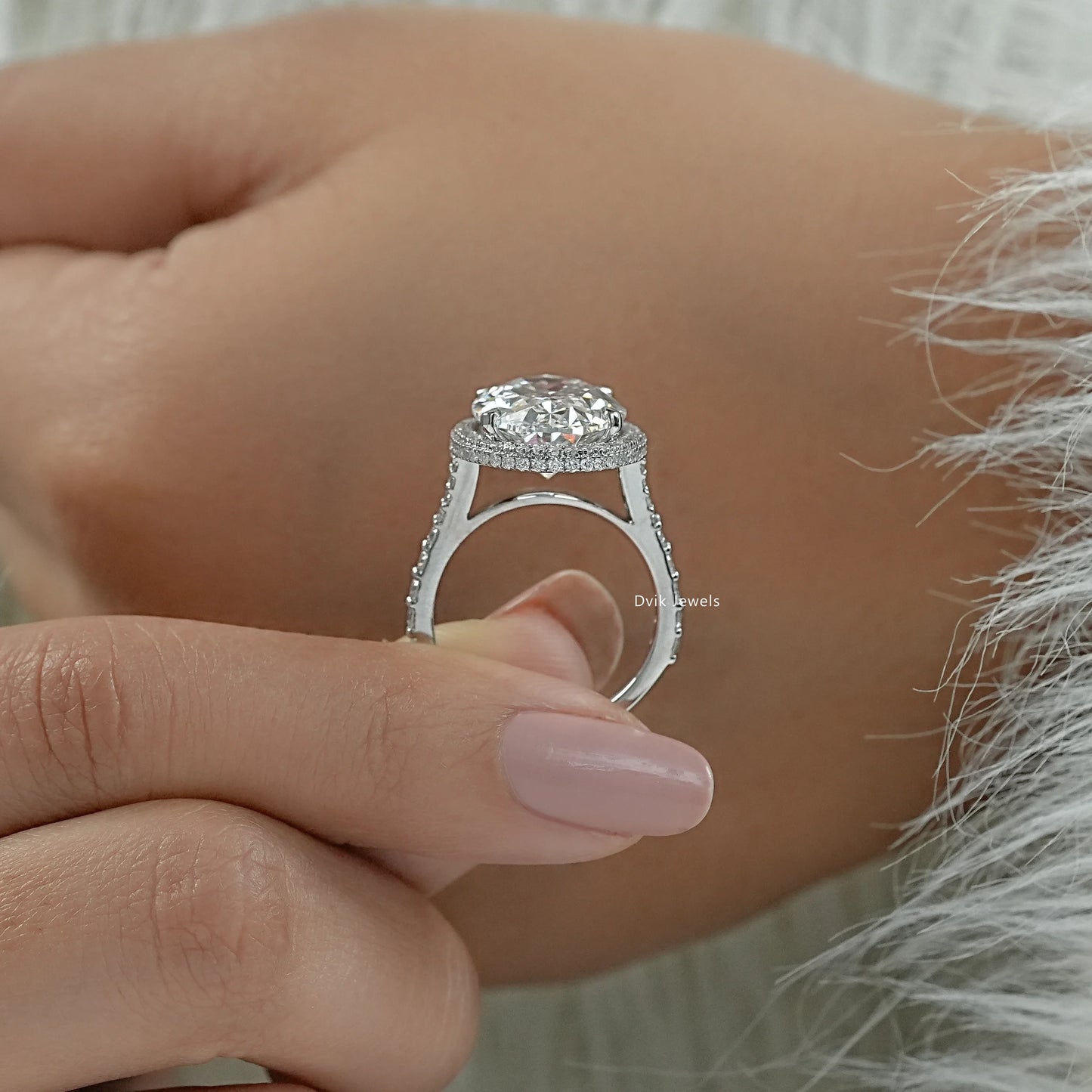 Lab grown halo diamond ring held between fingers to show the side profile