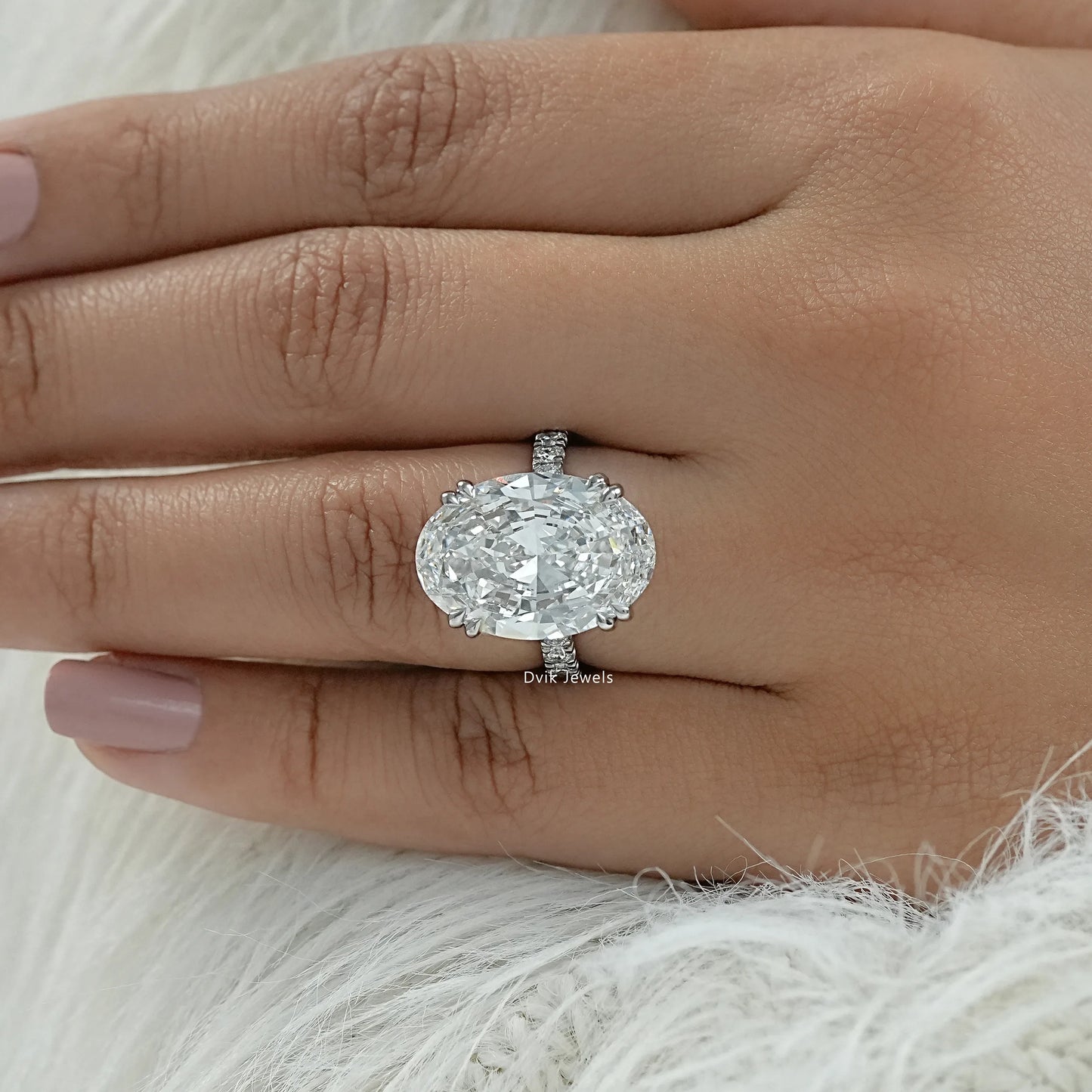 Oval engagement ring with hidden halo and side stones held for a side view