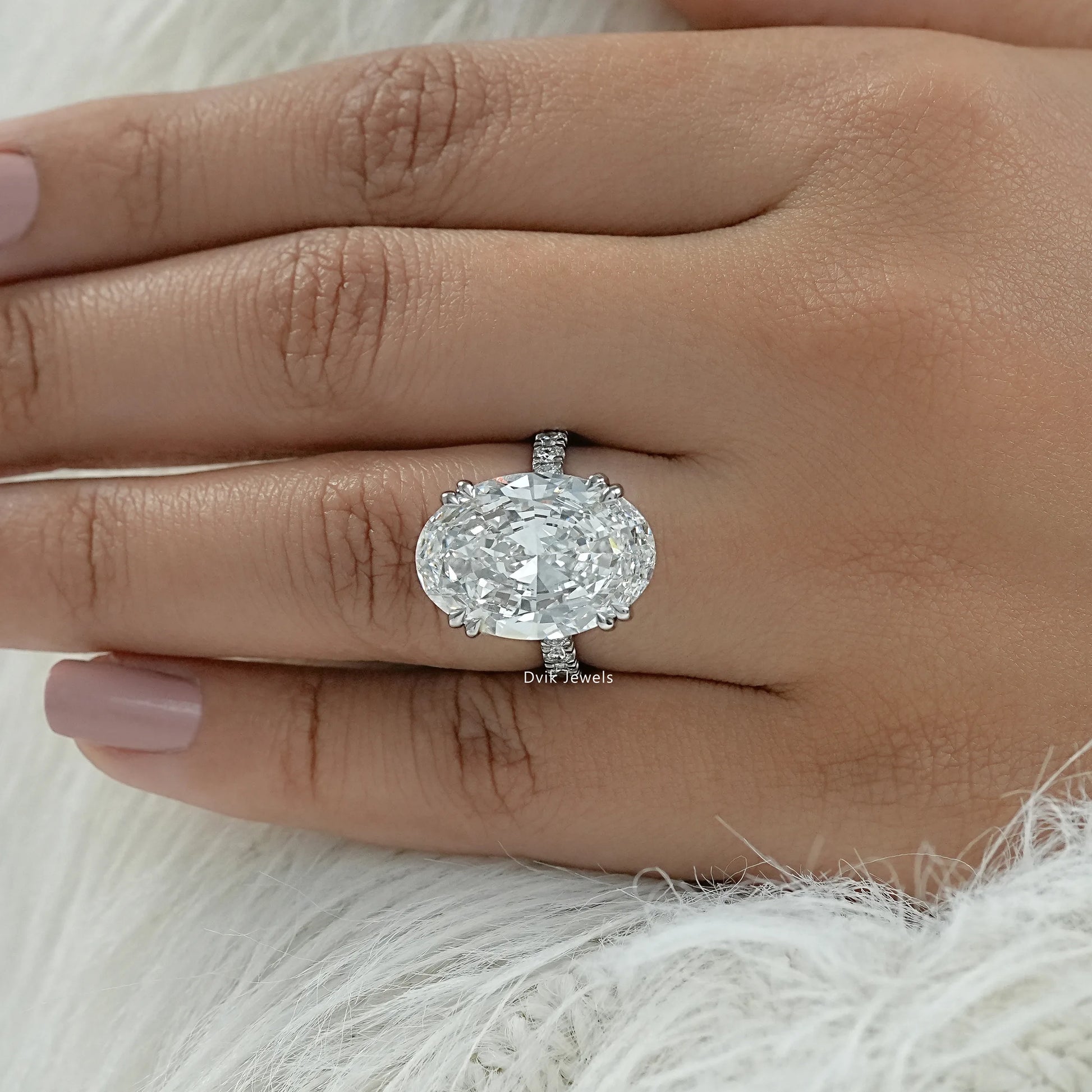 Oval engagement ring with hidden halo and side stones held for a side view