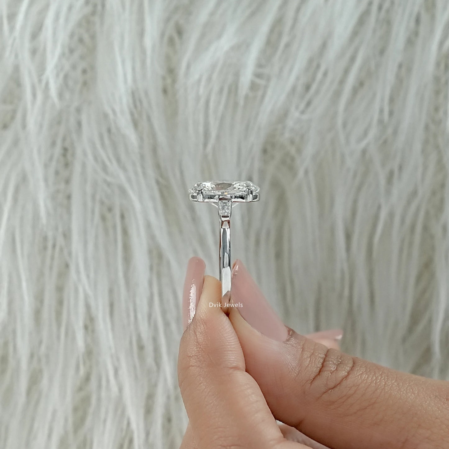 Macro view of oval engagement ring 3 carat held between fingers to show the stone's brilliance.