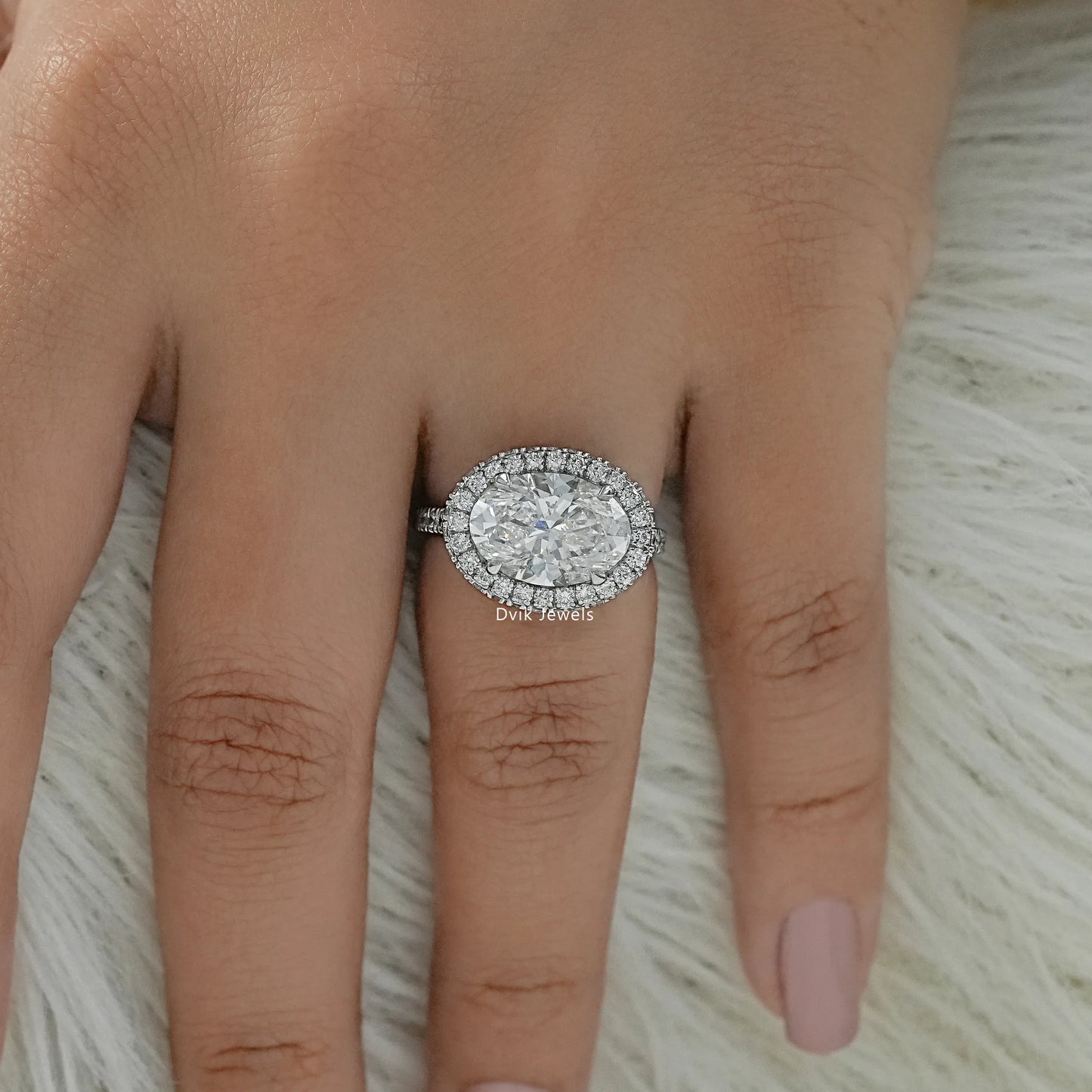 Oval engagement ring with halo worn on a hand to display the brilliant fit