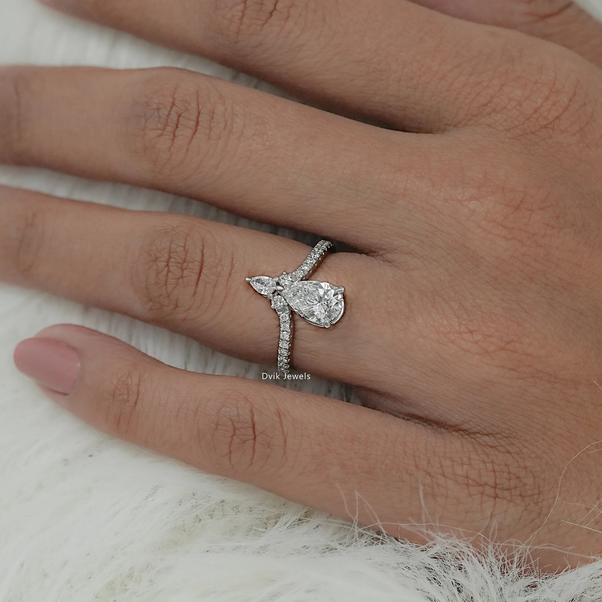 Close-up view of accent engagement ring featuring round center diamond with two pear cut diamond accents