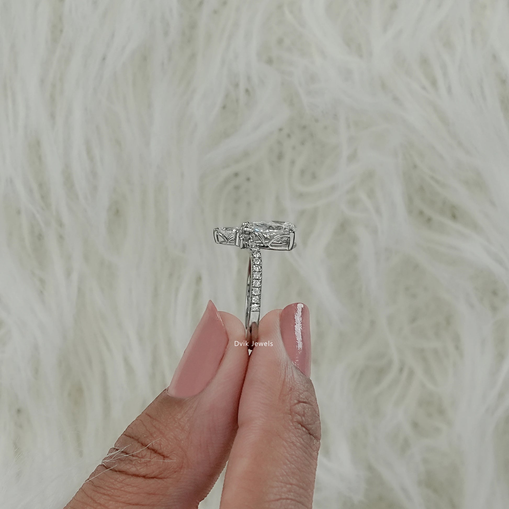 Pear diamond engagement ring with accent setting worn by model hand