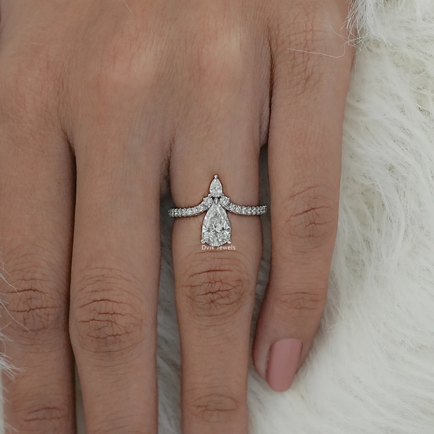 Women wear pear cut engagement ring on finger, showing symmetrical stone design