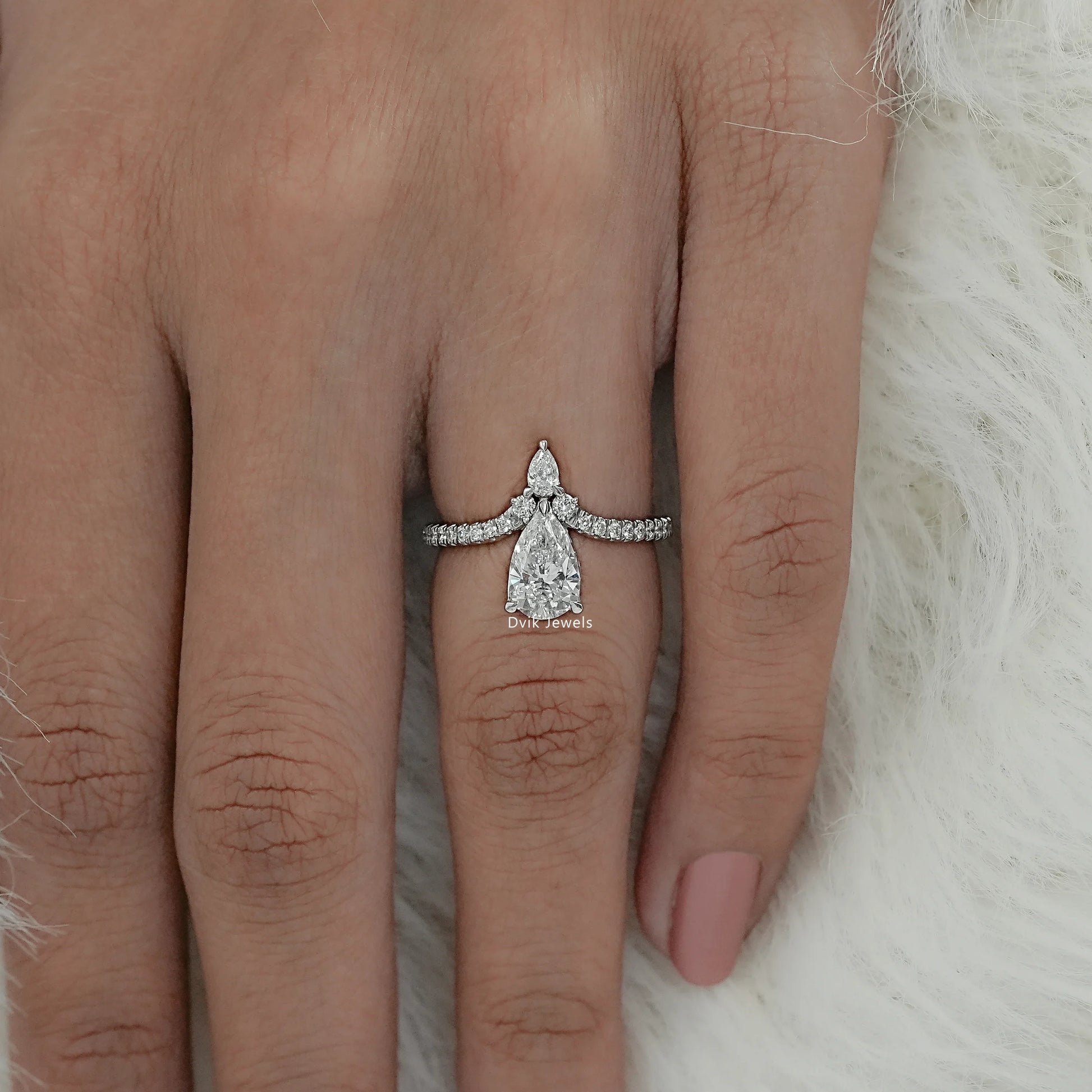 Women wear pear cut engagement ring on finger, showing symmetrical stone design