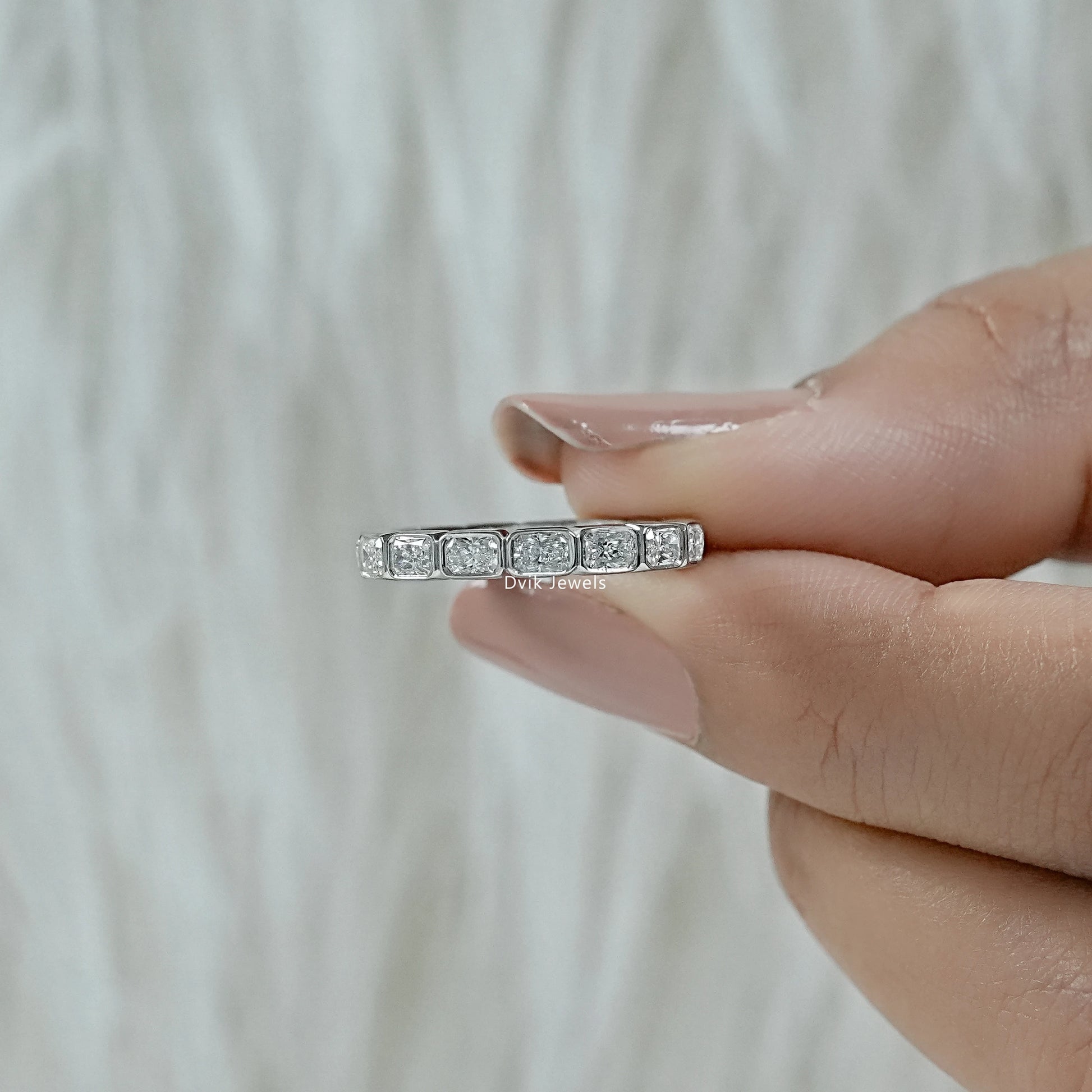 Bezel diamond eternity band held to show the modern polished metal