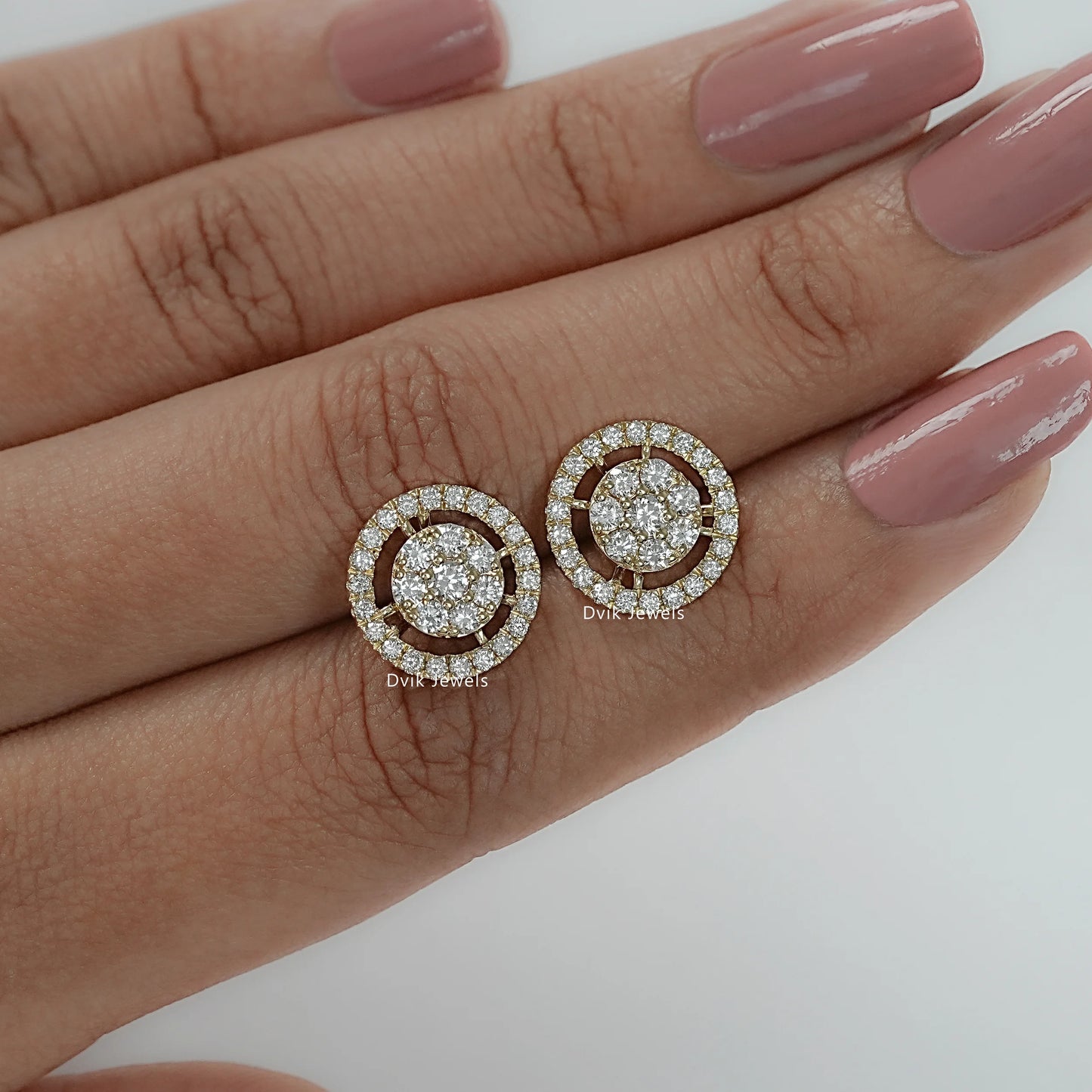 Pair of diamond stud earrings with halo cluster on finger, perfect diamond gifts for women
