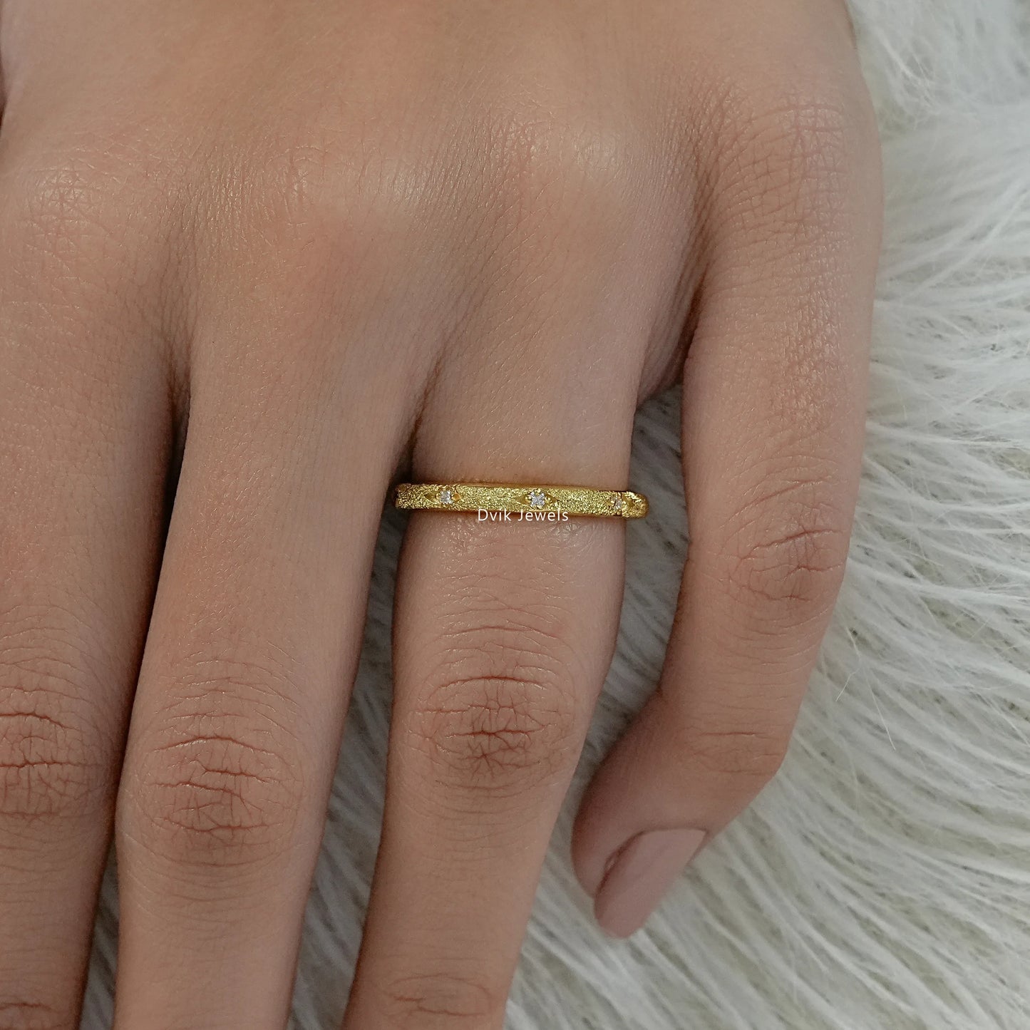 Round diamond eternity band yellow gold textured finish on hand