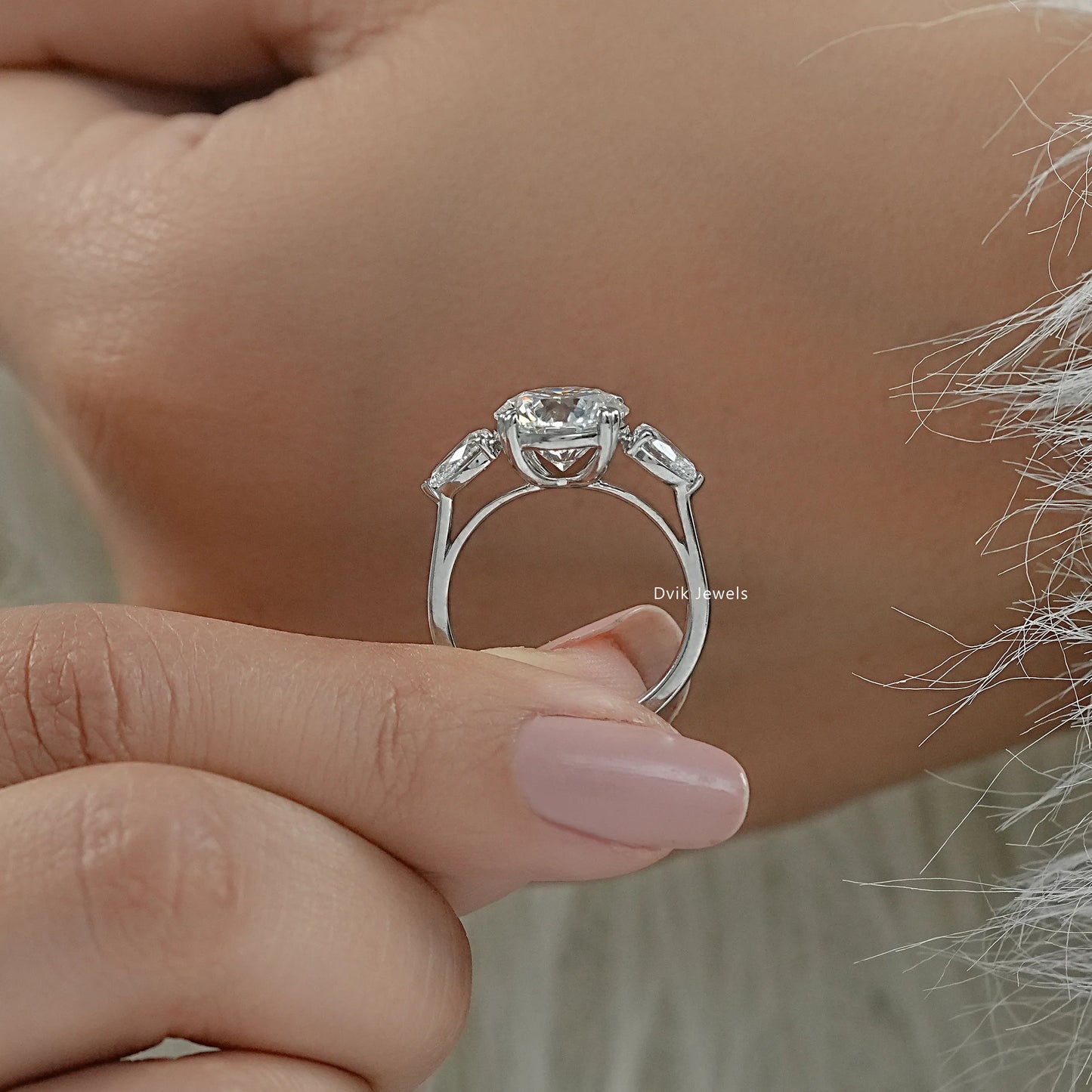 Round engagement ring with pear side stones double prong rings profile view