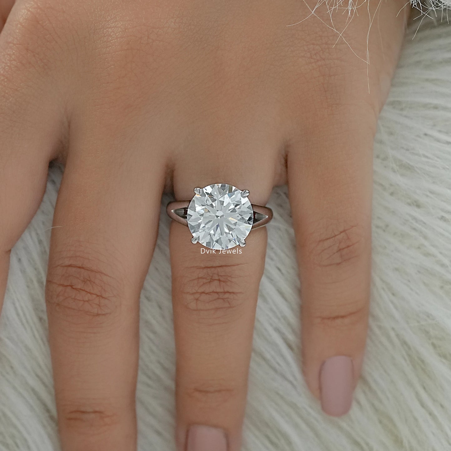 Round lab diamond engagement ring on finger top view
