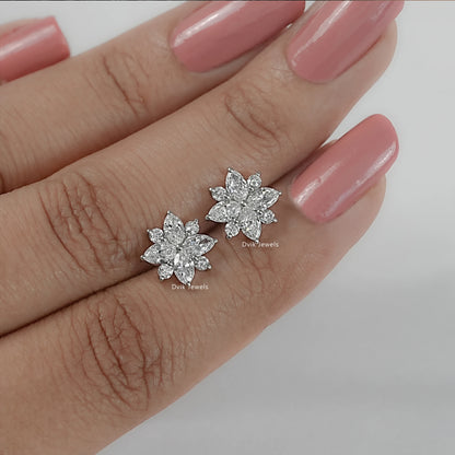 Floral diamond stud earrings held between fingers with round center stone