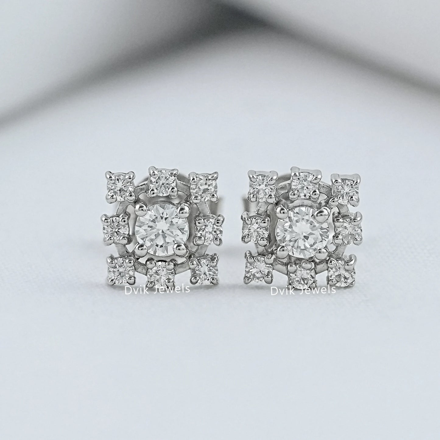 Angled view of halo studs earring on white fabric for our USA bridal jewelry market.