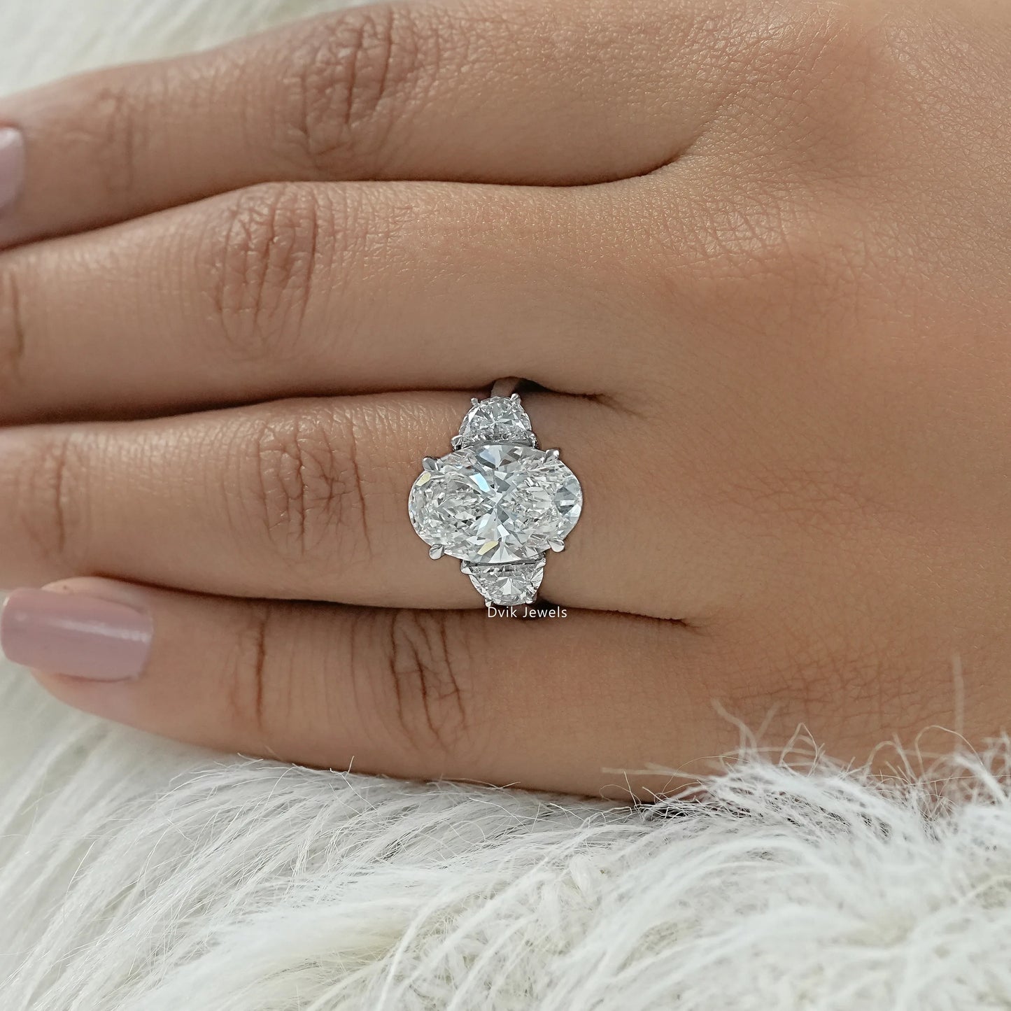 Oval engagement ring with half moons held to highlight the side stone clarity