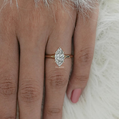 Top view of an elongated marquise diamond solitaire ring on a hand, highlighting sleek gold band