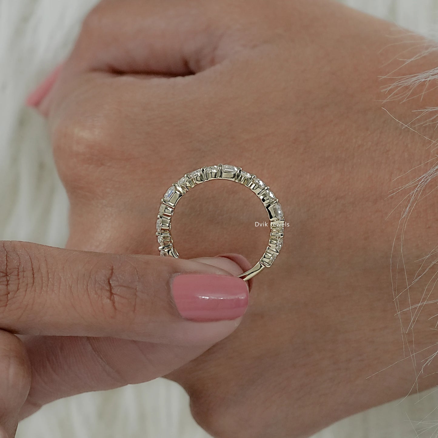 Women holding half eternity wedding bands with pear, oval emerald mixed diamond