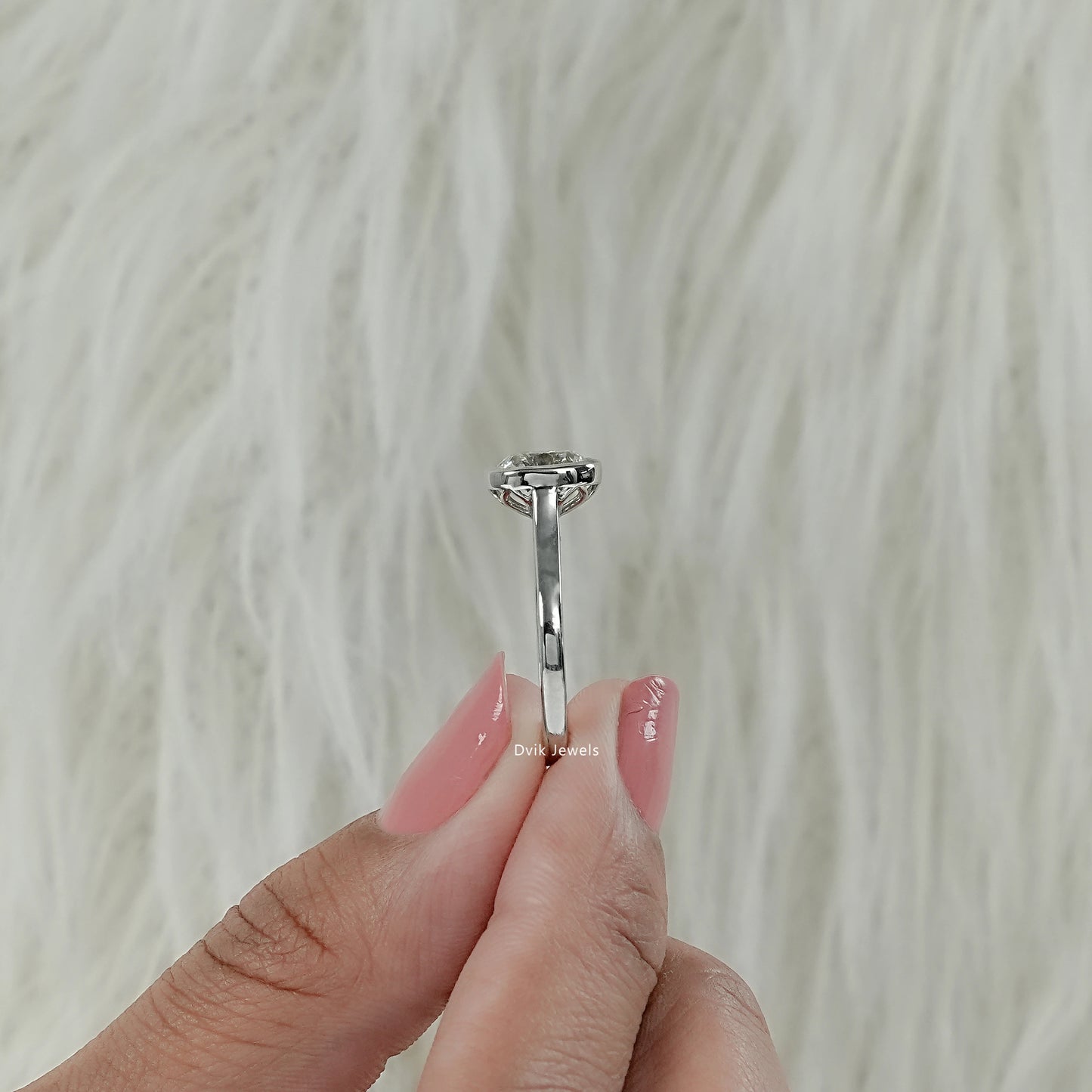 Vertical side view of old mine cut diamond ring with cushion cut diamond held between fingers for slim profile