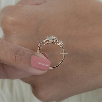 Women holding five stone ring with center pear-cut stone tapered by baguettes diamond