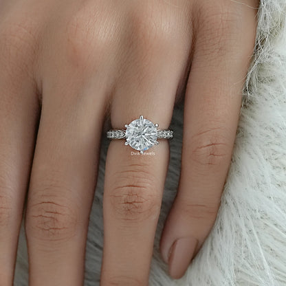 Round engagement rings with side stones in white gold V-shaped band.