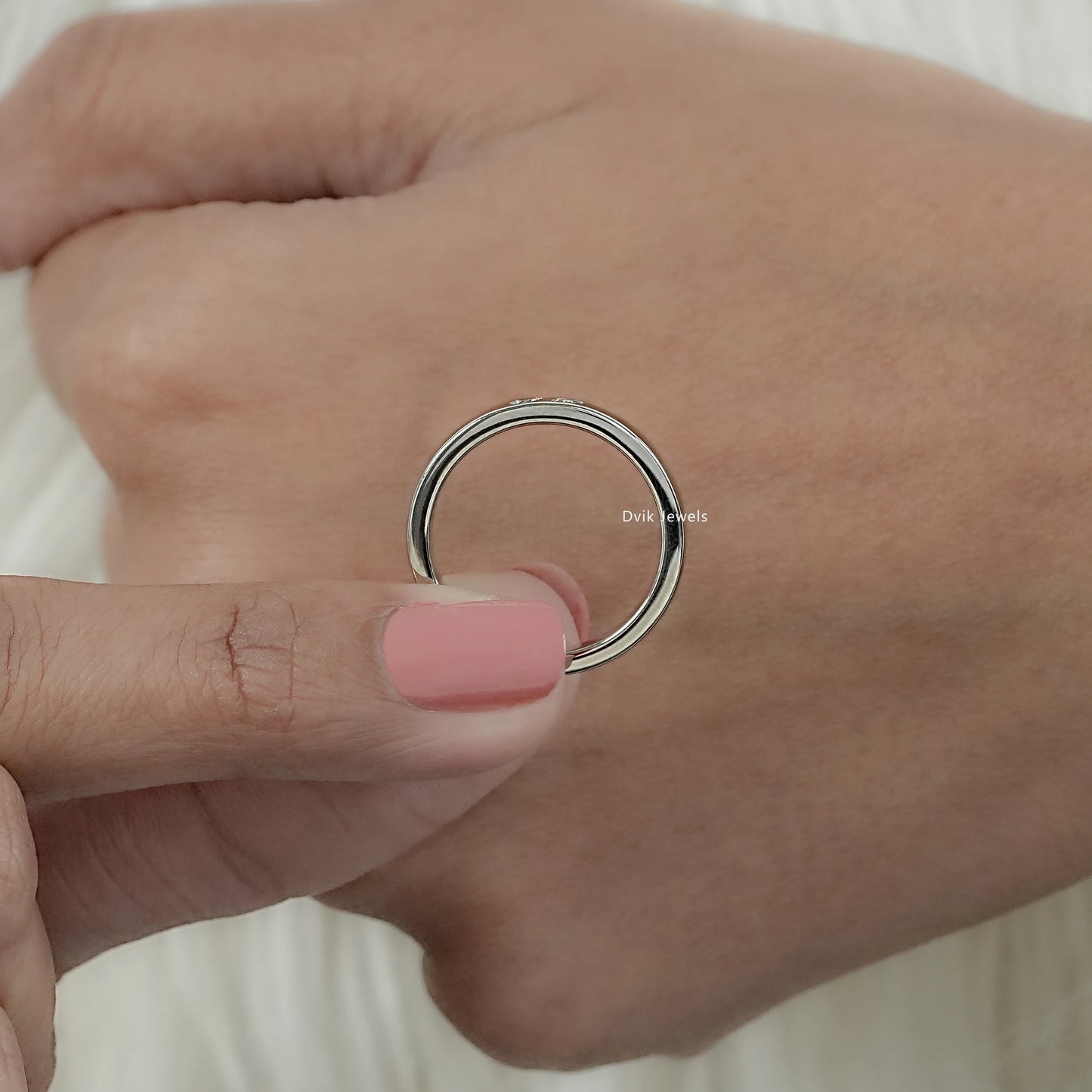 Slim wedding band with pear cut diamond held by women for middle view