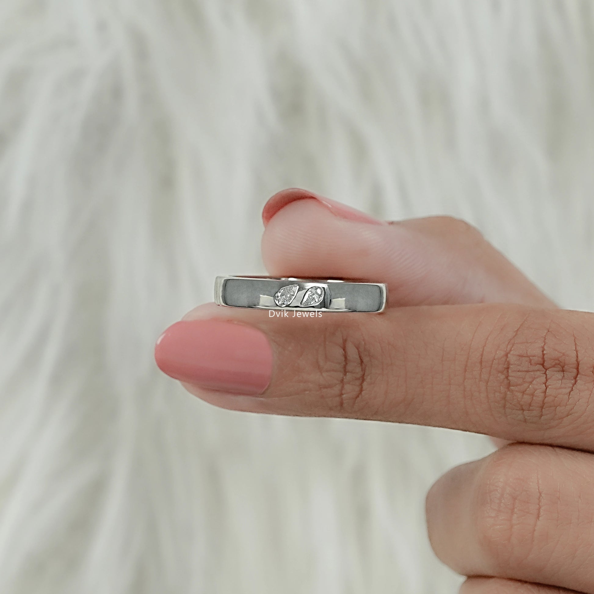 Twin pear cut lab diamond sleek band held by women for front view